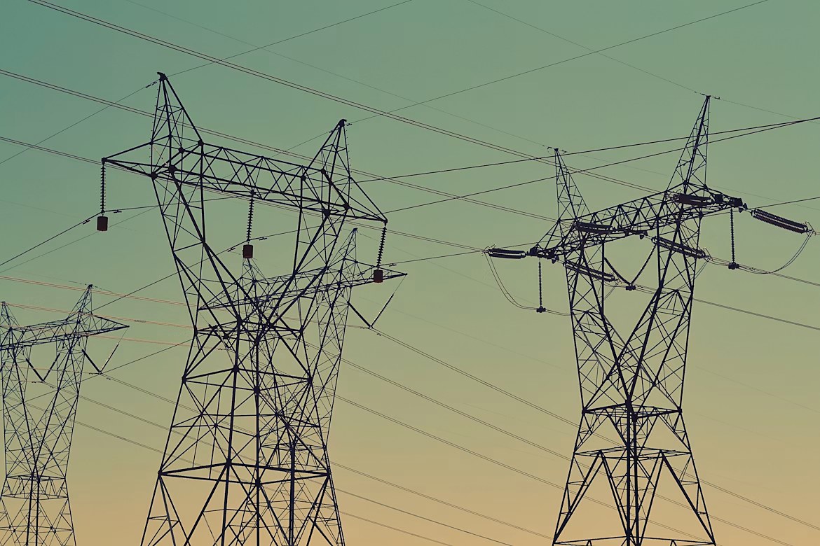 Transmission towers across an open field at dusk